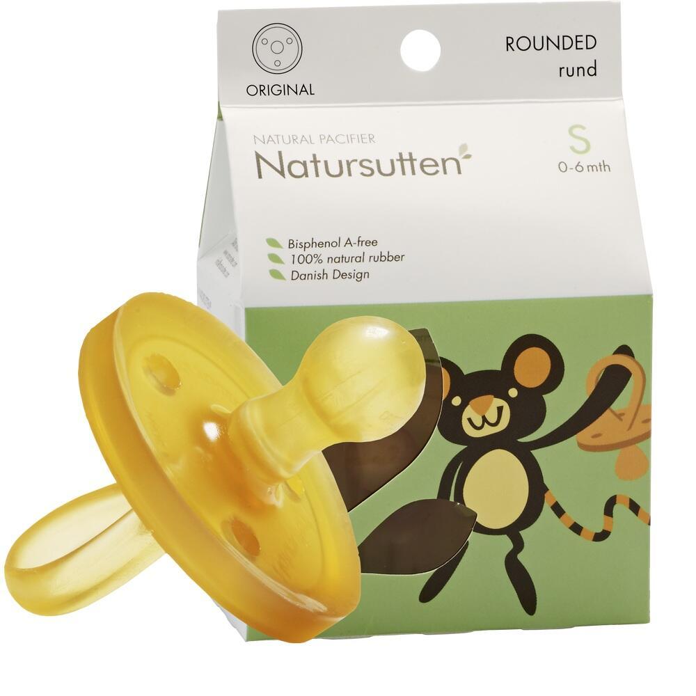 Gelber Schnuller vor einer Verpackung mit Affenmuster.