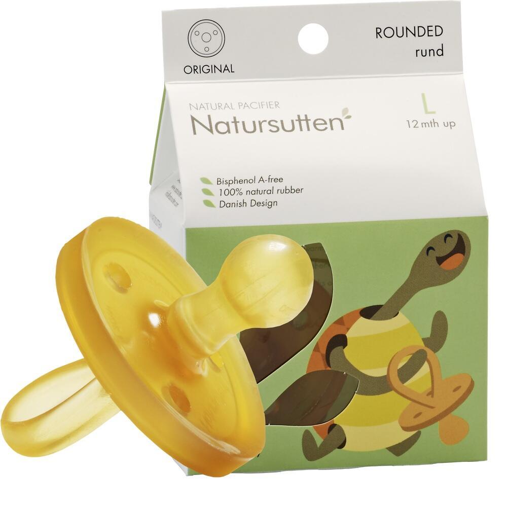 Gelber Schnuller vor einer Verpackung mit Schildkr&ouml;tenmotiv.