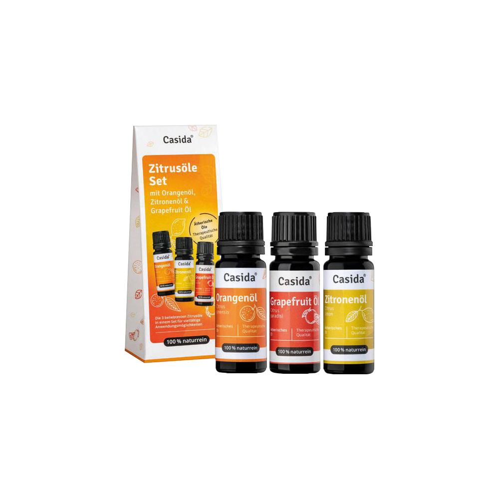 Drei Fläschchen mit Orangen-, Grapefruit- und Zitronenöl stehen neben der Verpackung.