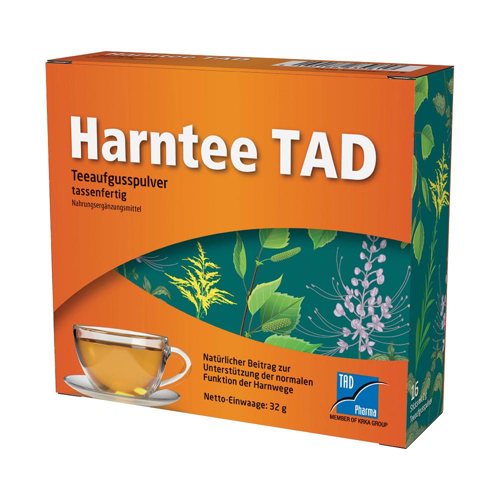 Orange Schachtel mit Tee in einer Tasse, umgeben von grünen Blättern.
